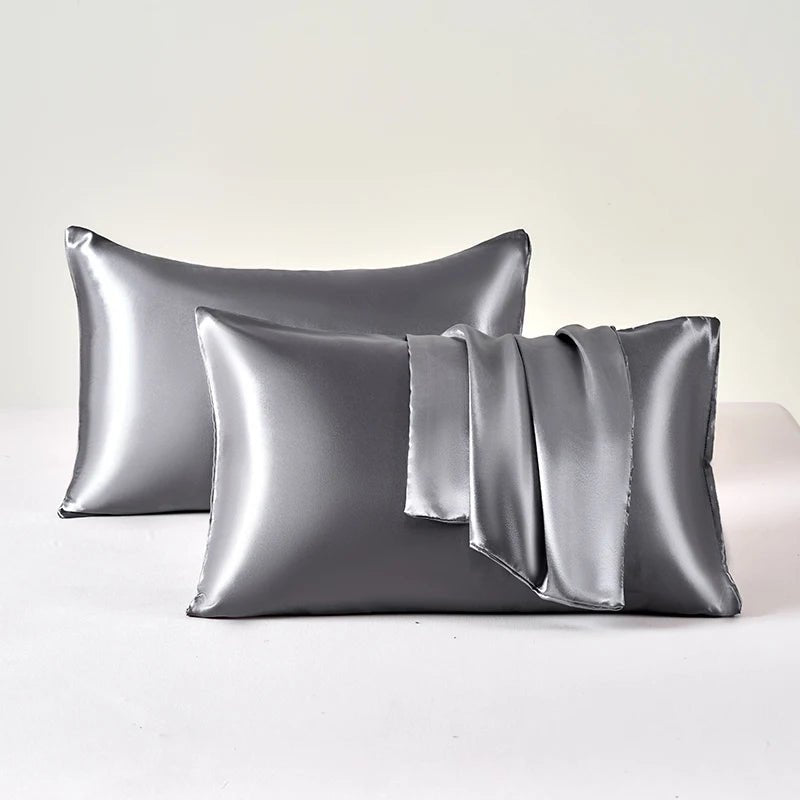 Two silver satin pillowcases on a white background