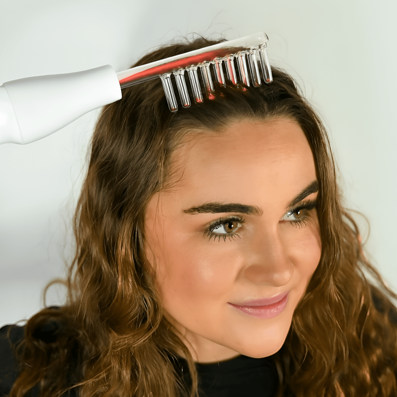 Woman using a hair dryer and brush on her hair against a white background