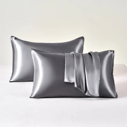 Two silver satin pillowcases on a white background